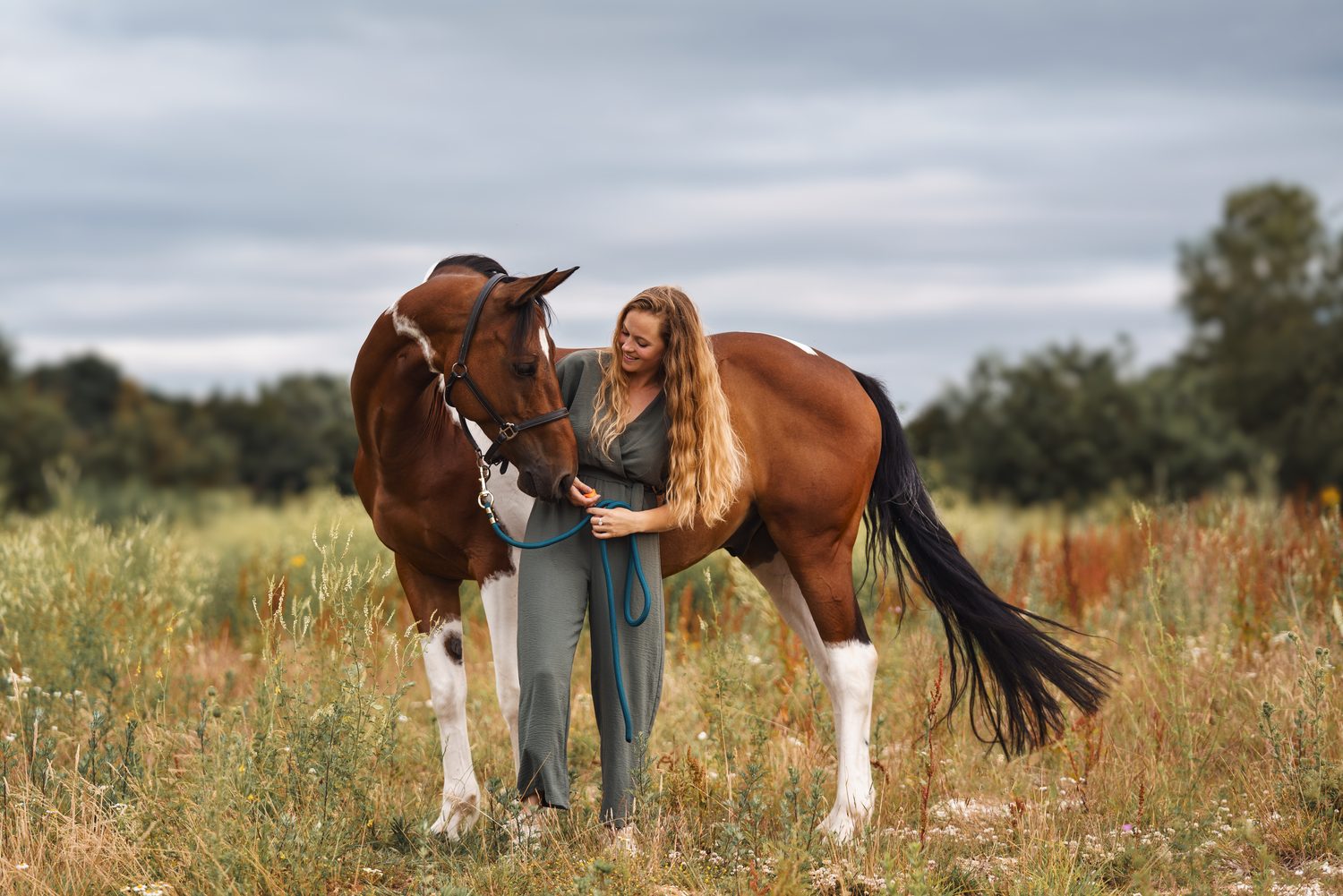 Cheval et sa propriétaire dans un champ au coucher du soleil
